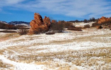 young hiker standing on trail with red rock formations and foothills in background in south valley park hike near littleton colorado