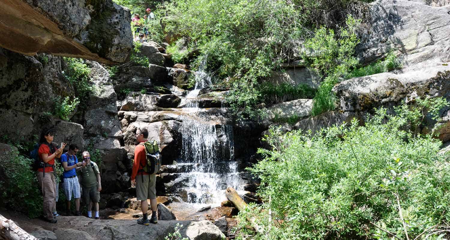 maxwell falls with waterfall and hikers above and at the base of the waterfall