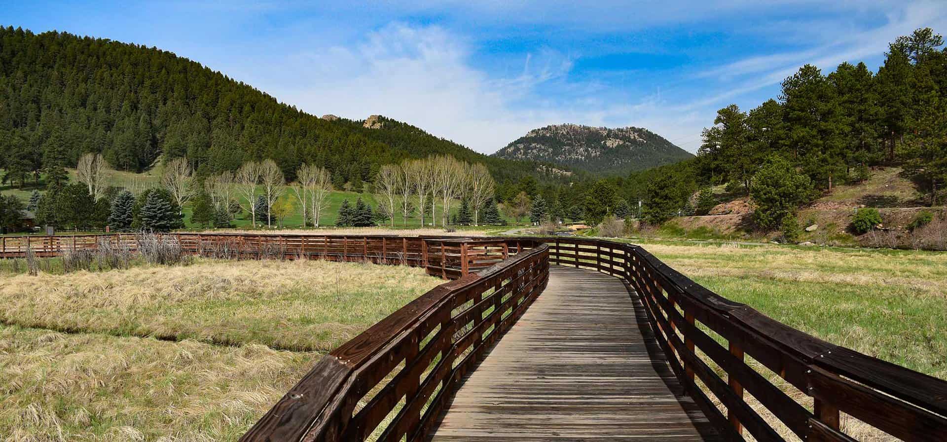 evergreen colorado boardwalk along evergreen lake with mountains and aspen trees in background