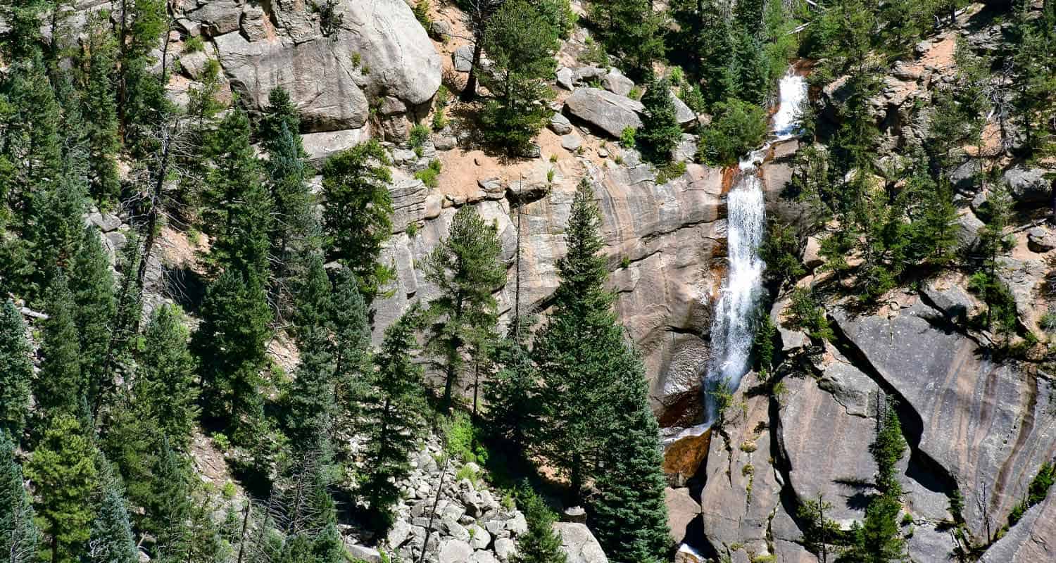 elk falls waterfall spilling over granite cliff faces with evergreen trees in staunton state park colorado