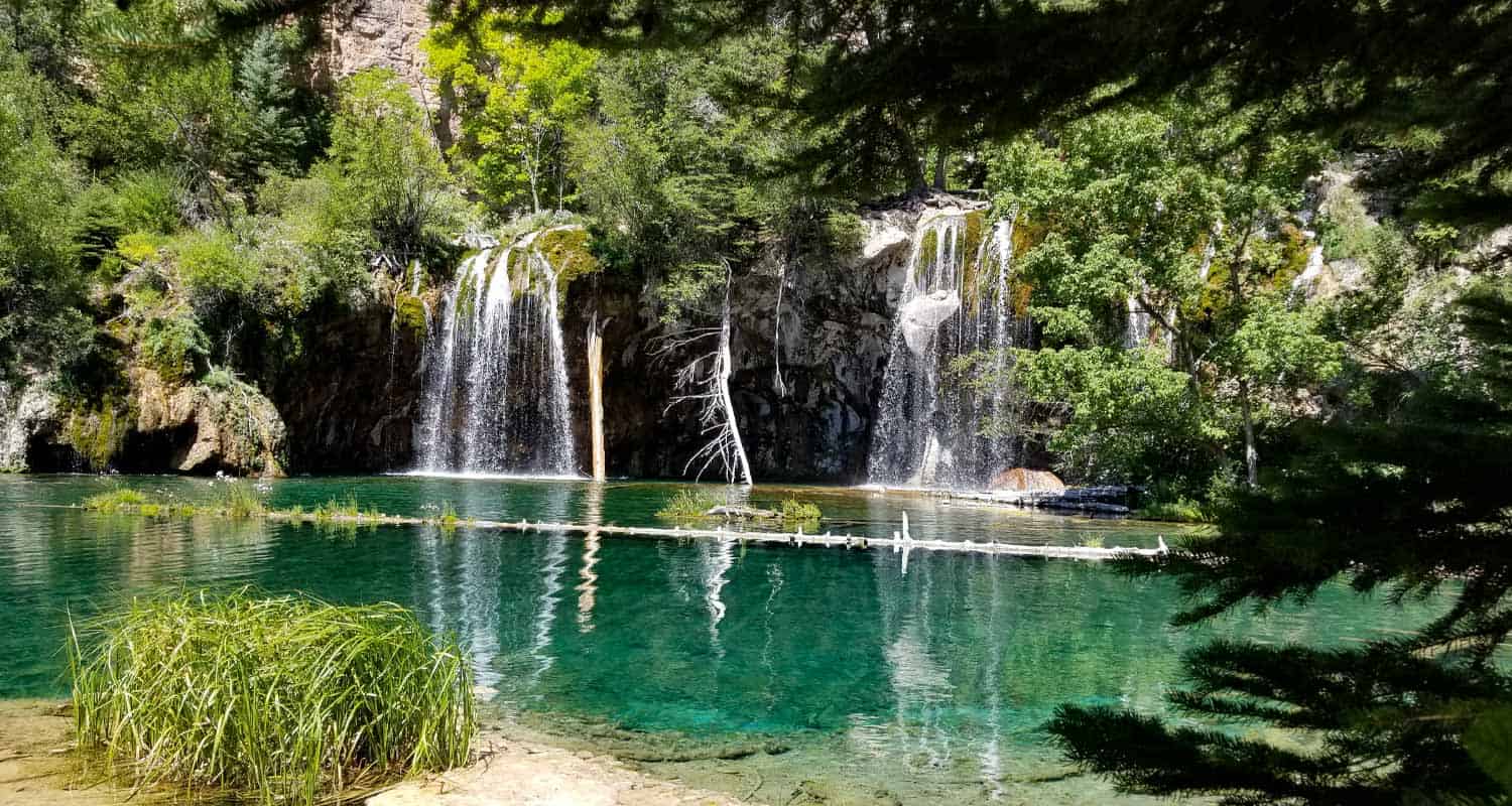 hanging lake waterfall flowing over verdant cliff face into turquoise pool on hike near glenwood springs colorao