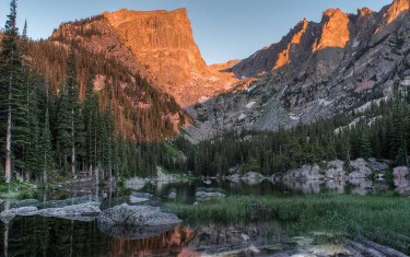 dream lake at sunrise in rocky mountain national park with mountain face of hallett peak in background