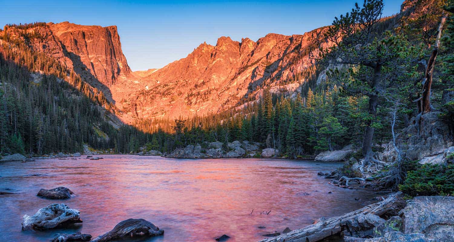 dream lake at sunrise in rocky mountain national park with mountain face of hallett peak in background