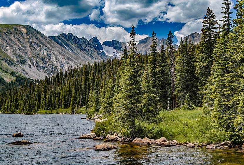long lake in indian peaks wilderness colorado clouds and blue sky with jagged moutnains, evergreen trees and lake