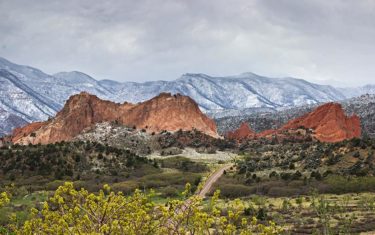 snow capped pikes peak in background and orange rock of garden of the gods in foreground
