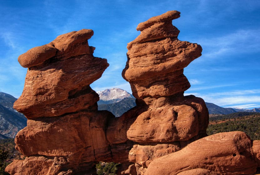 two red rock towers rock formation with pikes peak mountain in background