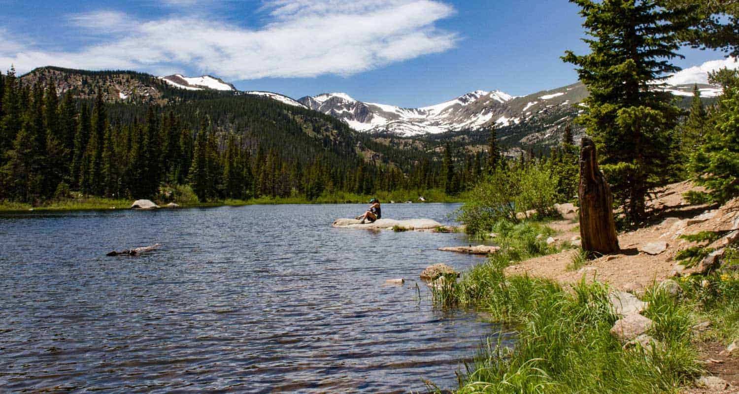 lost lake near nederland colorado with snow capped peaks and woman hiker