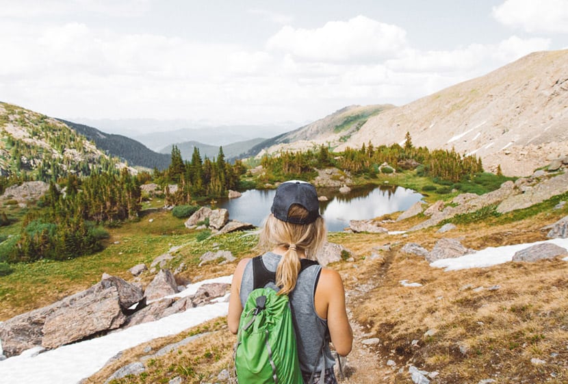 hiker in high country of colorado wearing hat with green backpack by colorado adventure photographer holly mandarich