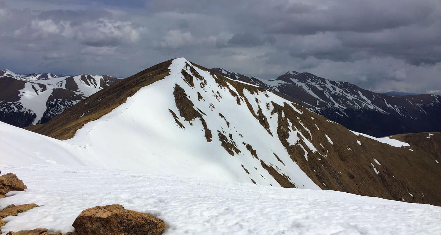 view toward mt sniktau along sniktau trail with snow in forground and grey skies in background